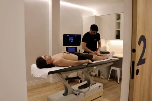 Mariano Caldés realizando tratamiento de fisioterapia avanzada en el pie de un paciente.